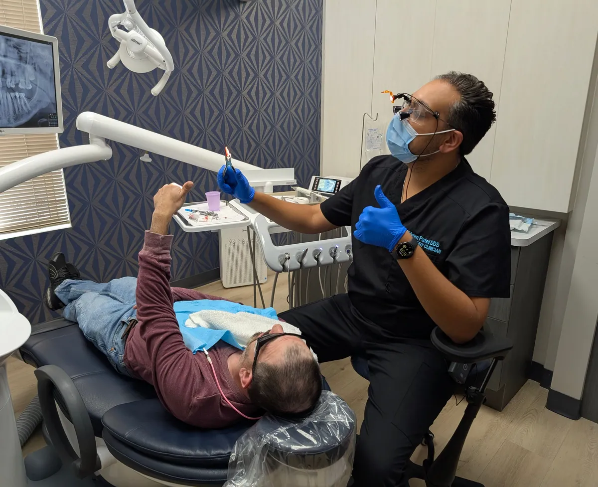 Dr. Shivam Patel giving a thumbs-up beside a smiling patient in a treatment room at Midwest Center for Dentistry and Implants
