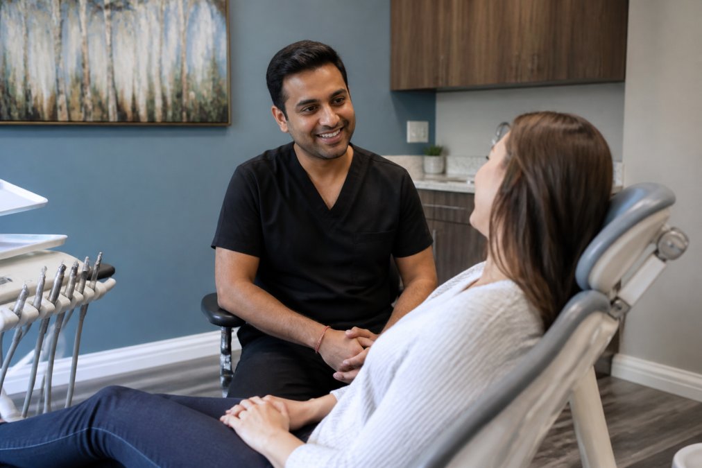 Patient in relaxed dental chair with calming ambient lighting and soothing wall colors, dentist nearby showing a reassuring expression during initial consultation
